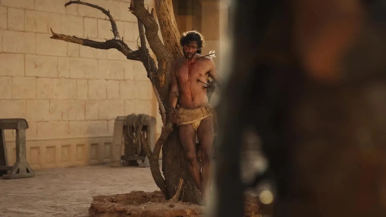 Still from "Martin Scorsese Presents: The Saints." Saint tied to tree wearing loincloth.