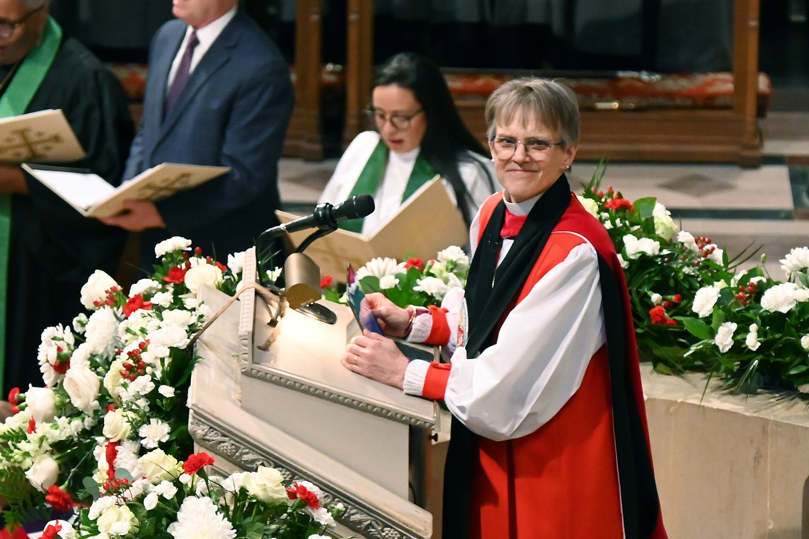 Bishop Mariann Budde, Washington National Cathedral, Jan. 21, 2025. Bishops stands at ambo, smiling at camera.