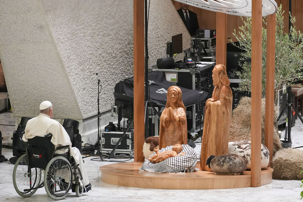 Pope Francis, keffiyeh nativity scene, Vatican, Dec. 7, 2024. Francis in wheelchair pictured from behind regarding the nativity scene.