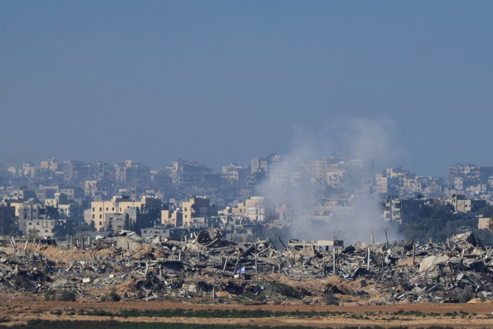 Rubble in Gaza An Israeli flag flies next to the rubble of destroyed buildings Dec. 26, 2023, as smoke rises in the Gaza Strip, as seen from southern Israel.
