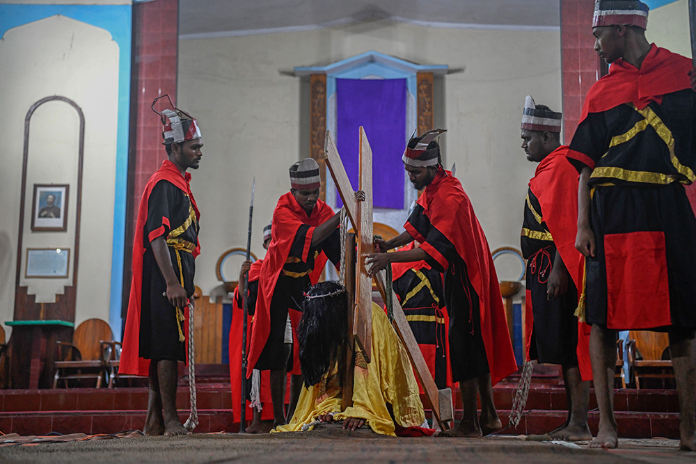 The cross is placed on Jesus' shoulder during the Way of the Cross reenactment. (Piyas Biswas)