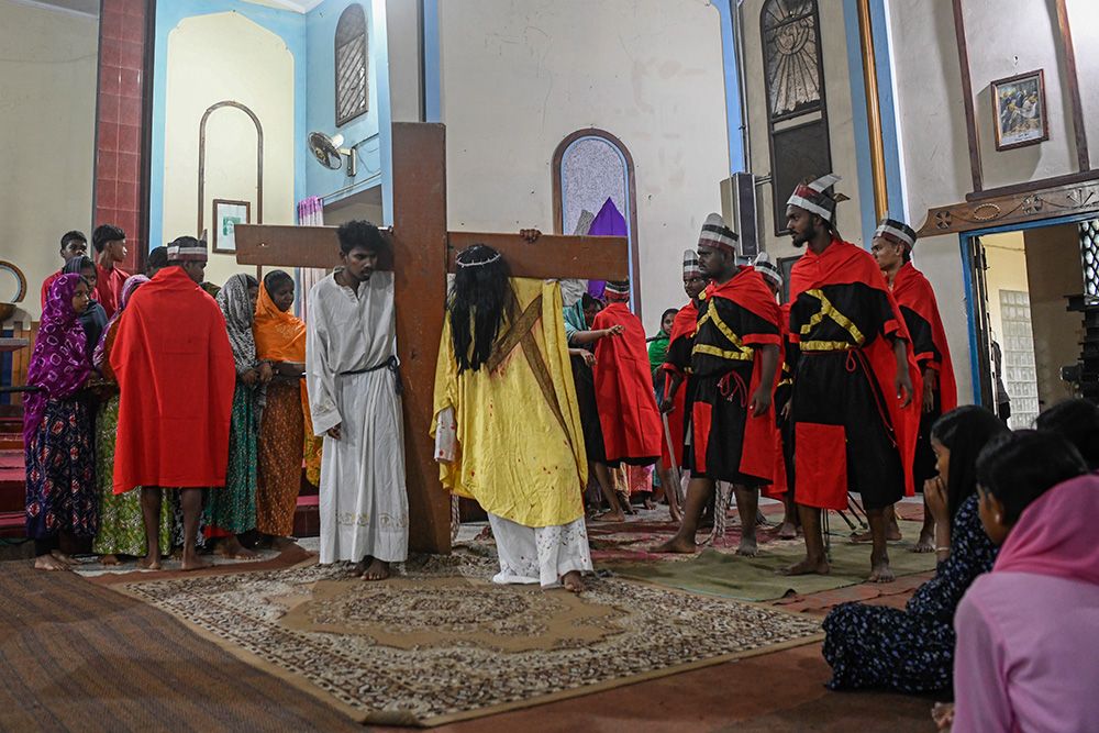 Simon of Cyrene helps Jesus carry the cross during the Way of the Cross. (Piyas Biswas)