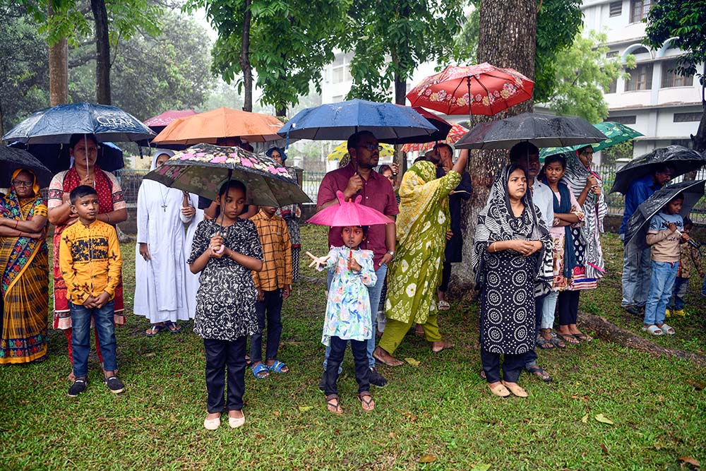 A child delights in the raindrops during the Way of the Cross, standing under the open sky in front of Dinajpur Cathedral. (Piyas Biswas)