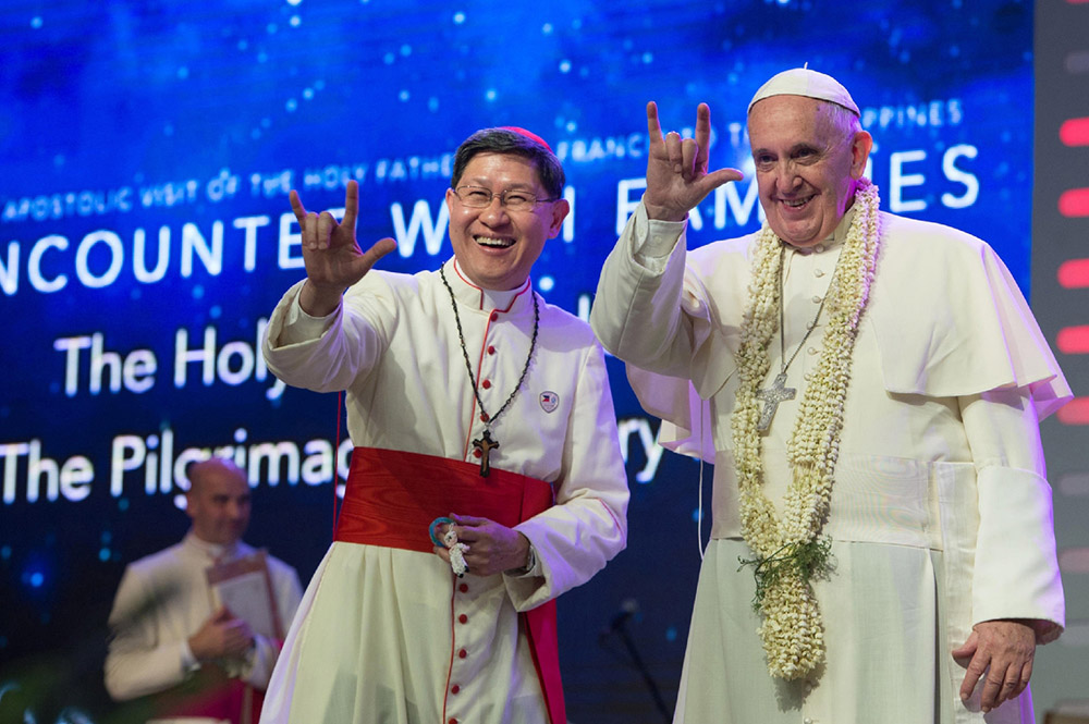 Pope Francis and Cardinal Luis Antonio Tagle say, "I love you," in sign language during a meeting with families in the Mall of Asia Arena in Pasay City, Philippines, Jan. 16, 2015. (CNS/L'Osservatore Romano via Reuters)