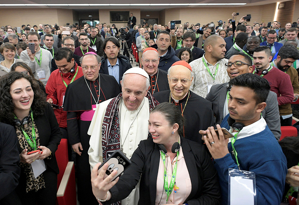 Pope Francis poses for a selfie during a pre-synod gathering of youth delegates, including NCR contributor Nicole M. Perone, far left, at the Pontifical International Maria Mater Ecclesiae College in Rome on March 19, 2018. The meeting was in preparation for the Synod of Bishops on young people, the faith and vocational discernment this October at the Vatican. (CNS/Vatican Media)