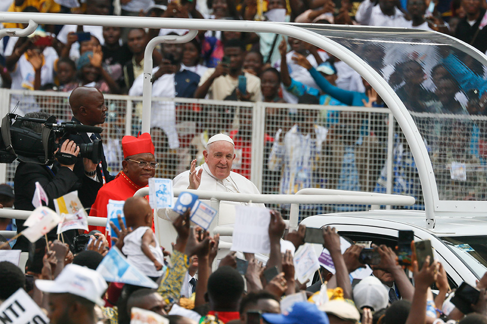 Cardinal Fridolin Ambongo rides in the popemobile with Pope Francis, who greets the crowd at the start of a meeting with young people and catechists in Martyrs' Stadium in Kinshasa, Congo, Feb. 2, 2023. (CNS/Paul Haring)