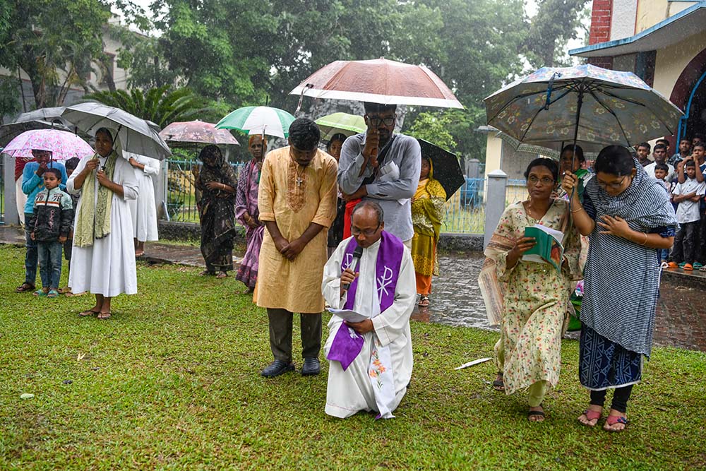 Holy Cross Fr. Bidya Barman leads the prayer during the Way of the Cross as it rains outside Dinajpur Cathedral. (Piyas Biswas)