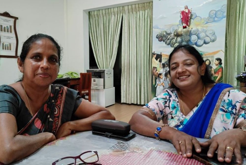 Two women sit at table.