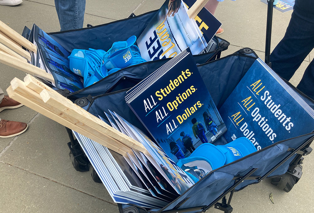 A cart full of placards is by the steps of the U.S. Supreme Court just prior to oral arguments determining if St. Isidore of Seville Catholic Virtual School in Oklahoma should get state taxpayer support. (NCR photo/Carol Zimmermann)