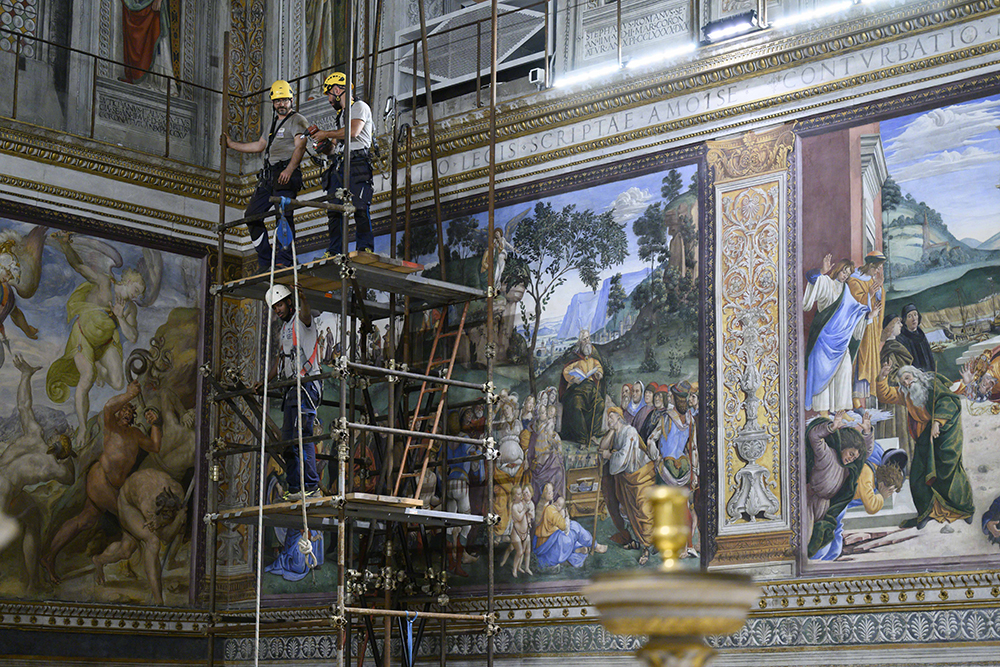 Workers on scaffolding May 2, 2025, attach the stove pipe to the stove that will be used to burn ballots during the conclave to elect a new pope in the Sistine Chapel at the Vatican. Cardinals under the age of 80 will enter the conclave May 7. (CNS/Vatican Media)