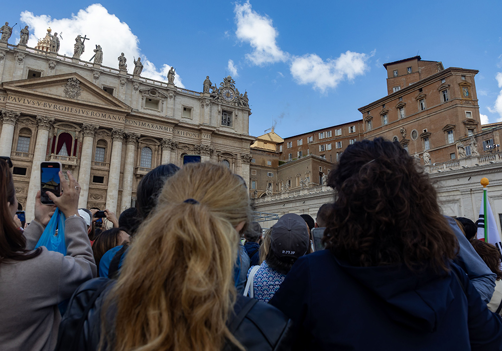 People watch as black smoke billows from the chimney on the Sistine Chapel May 8, 2025, on the second day of the conclave at the Vatican. (CNS/Pablo Esparza)