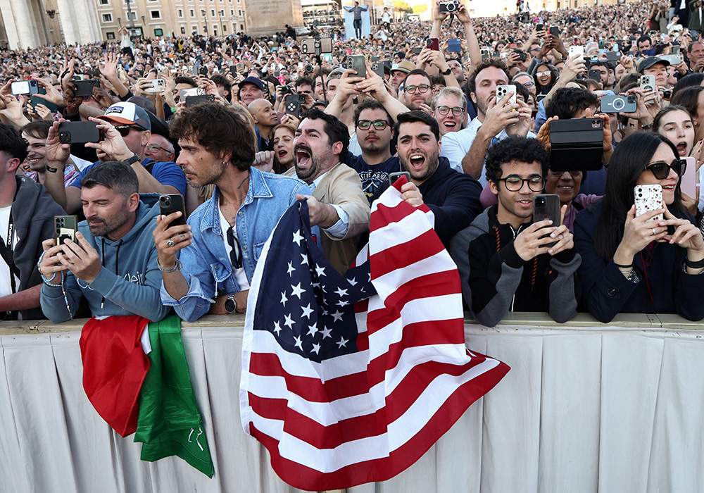 Men wave a U.S. flag as Cardinal Robert Francis Prevost, who has chosen the papal name Leo XIV, appears on the central balcony of St. Peter's Basilica at the Vatican May 8, 2025, following his election during the conclave. He is the first pope from the United States in history. (OSV News/Reuters/Eloisa Lopez)