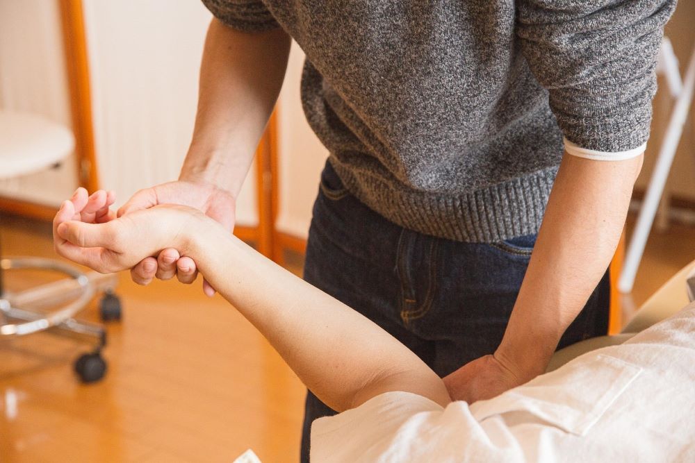 Physical therapist moves patient's arm. Physical therapist moves patient's arm.