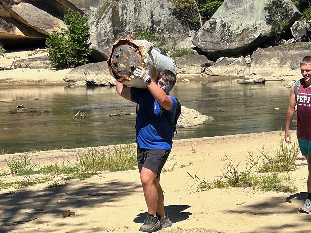 A University of Kentucky student removes a water heater from the Cumberland River as part of an environmental cleanup in August 2024 organized by the campus Newman Center. (Kevin Steele)