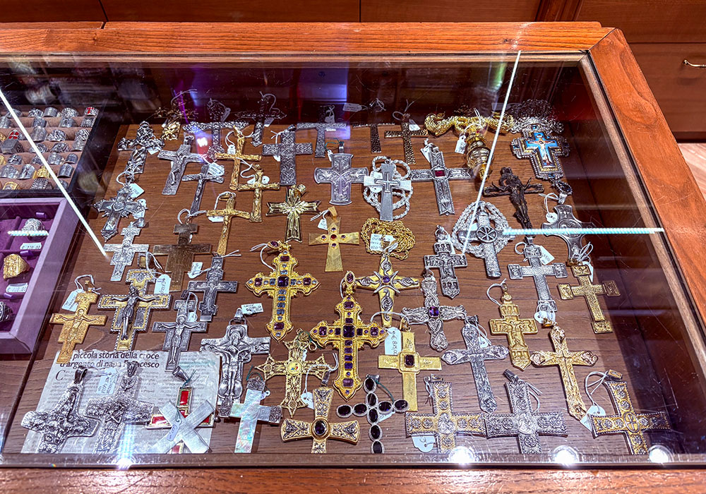 Pectoral crosses for bishops and cardinals are displayed in Raniero Mancinelli's store in Rome. On the bottom left is a cross with the same design that Pope Francis bought in the store when he was auxiliary bishop in Buenos Aires. An image of that cross is now depicted above his tomb in the basilica of St. Mary Major. (Camillo Barone)