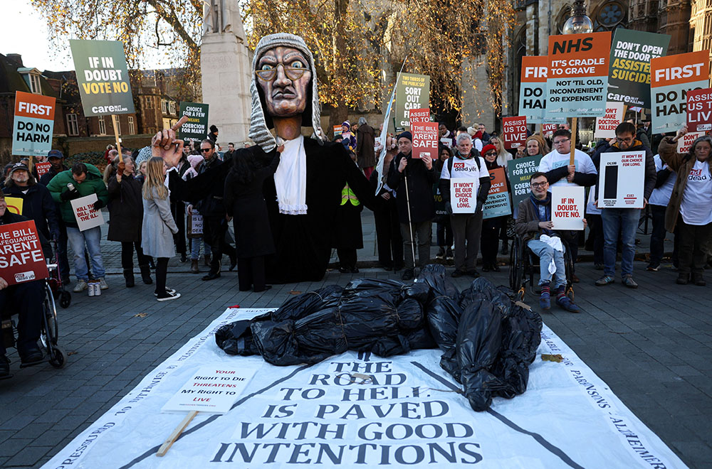 Protesters hold placards as they gather outside the Parliament as British lawmakers debate the assisted dying law in London on Nov. 29, 2024. (OSV News/Reuters/Mina Kim)