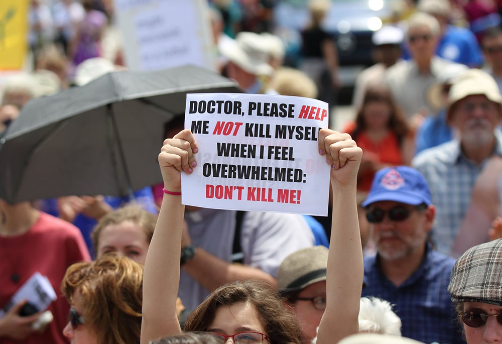 A woman is pictured in a file photo holding up a sign during a rally against assisted suicide on Parliament Hill in Ottawa, Ontario. (OSV News/Art Babych)
