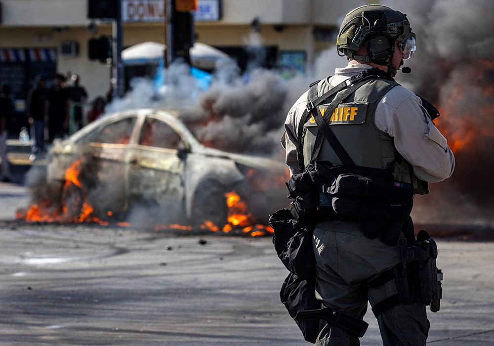 Smoke rises from a burning car on Atlantic Boulevard during a standoff by protesters and law enforcement, following multiple detentions by U.S. Immigration and Customs Enforcement in Compton, California, on June 7, 2025. (OSV News/Reuters/Barbara Davidson)