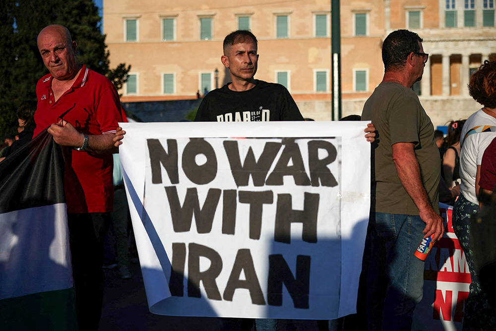 A demonstrator holds a sign during a protest over U.S. strikes on nuclear sites in Iran, in Athens, Greece, June 23, 2025. (OSV News/Reuters/Louiza Vradi)