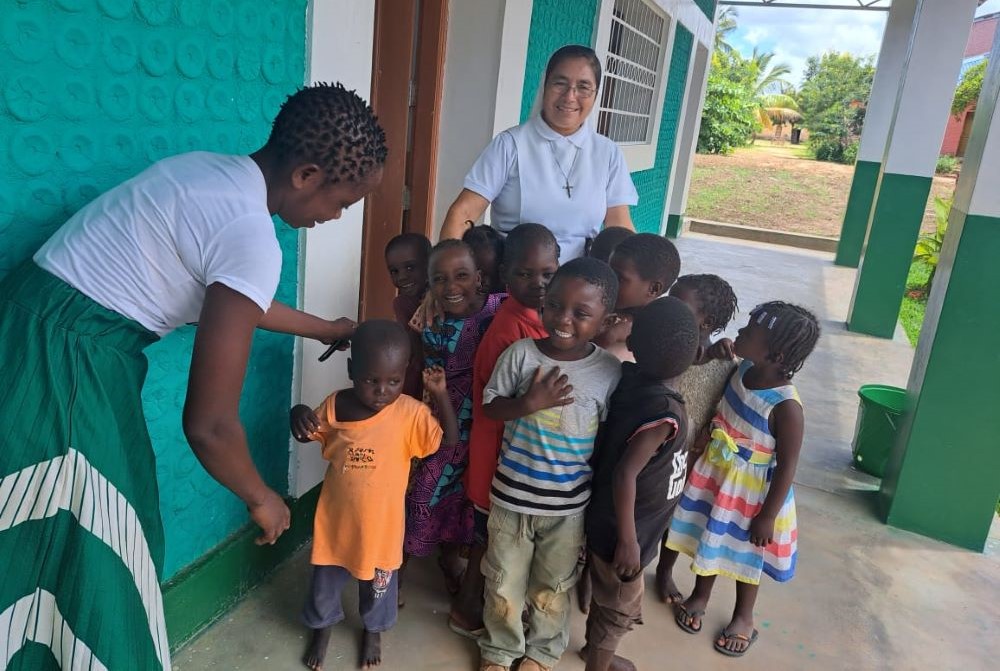 Sr. Aurora Jacinto stands with children outside a classroom made of plastic bottles. 