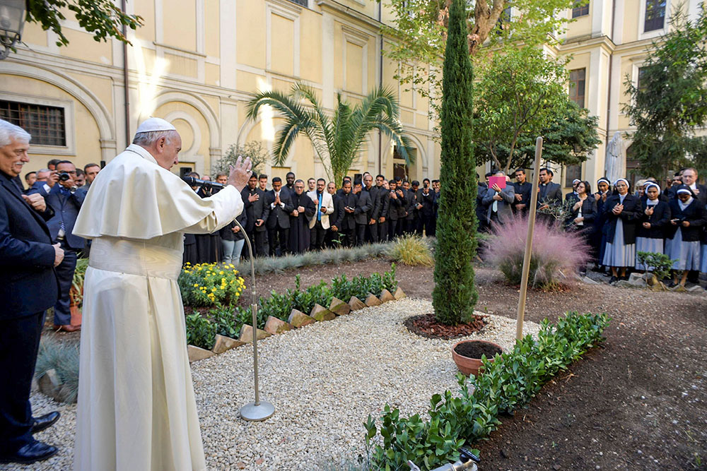 Pope Francis blesses a tree during a visit to the Jesuit-run Pontifical Oriental Institute in Rome Oct. 12, 2017. To the left is Jesuit Fr. Arturo Sosa, superior general of the Jesuits. (CNS/Vatican Media)