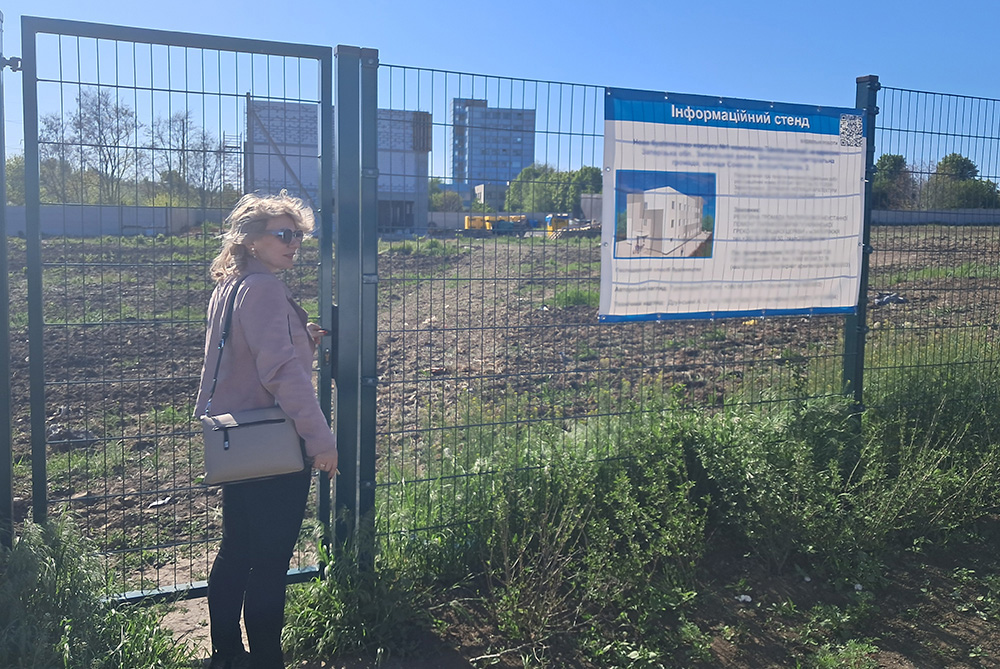 St. Don Bosco School principal Vitalia Vovk stands at the entrance to the site of a future school campus in Zaporizhzhia, in southern Ukraine (sign obscured for safety reasons). After two years of underground classes, Don Bosco's administrators started construction on a new school that will include both aboveground and belowground classroom space. (Marc Roscoe Loustau)