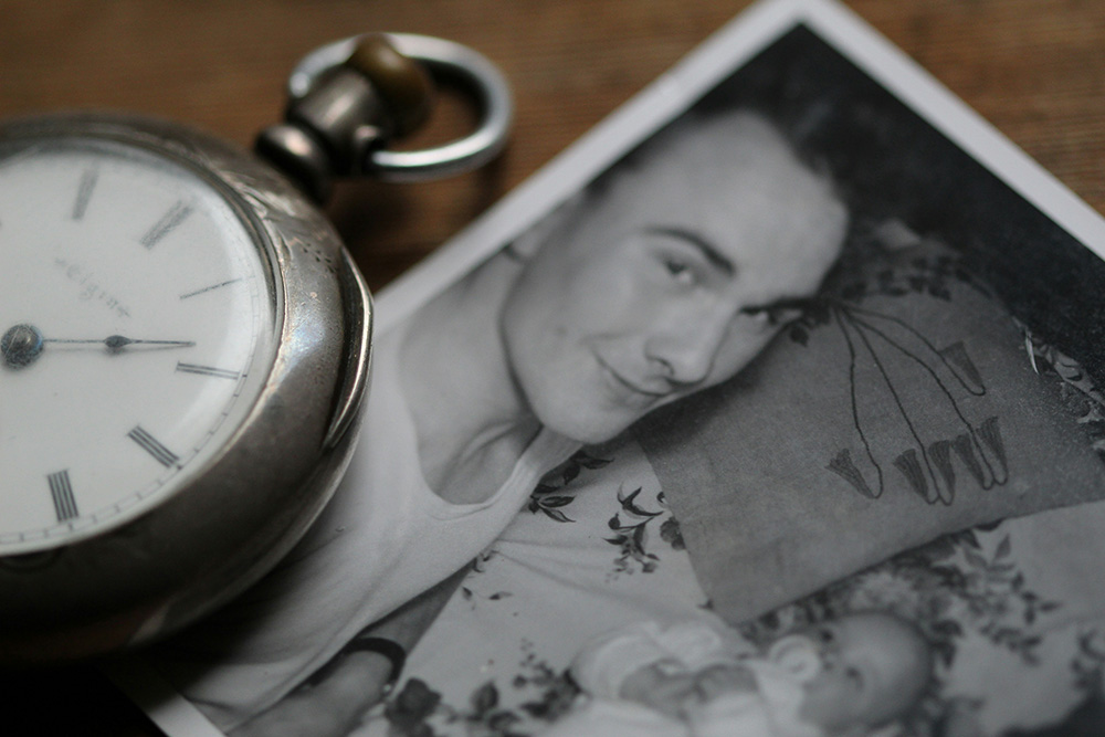 A pocket watch next to an old photograph of a father and child (Unsplash/Anne Nygard)