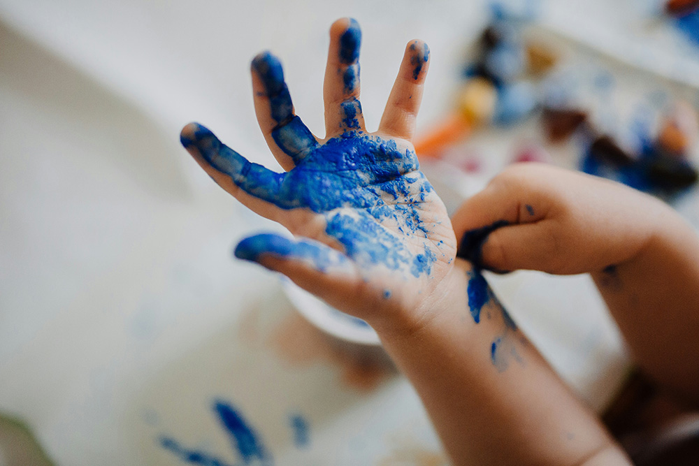 A child's hand with blue paint (Unsplash/Phil Hearing)