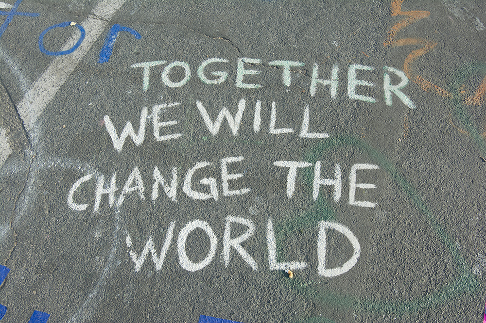 A phrase written in chalk on pavement says "Together we will change the world" (Unsplash/Priscilla Gyamfi)