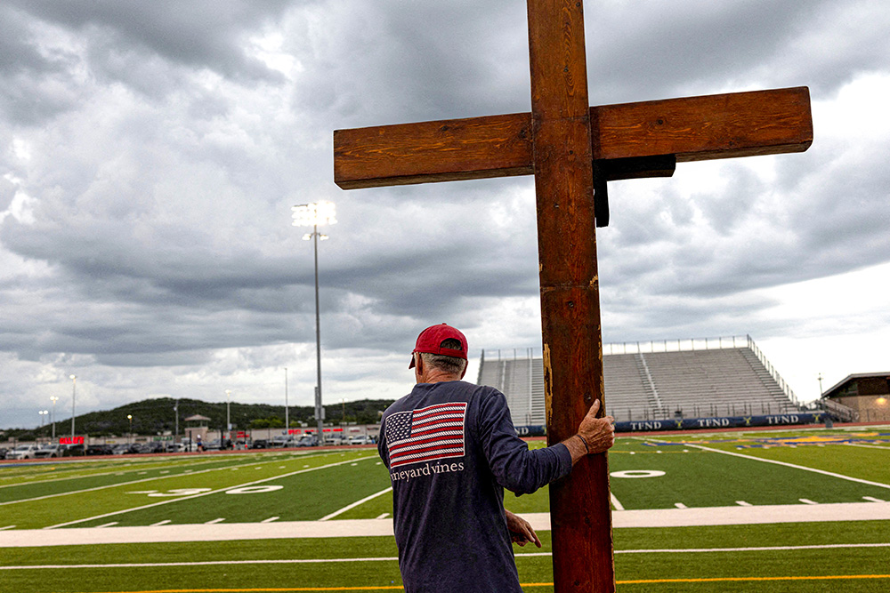 A man holds a cross during a prayer service for flood victims in Kerrville, Texas, July 9, 2025. (OSV News/Reuters/Umit Bektas)