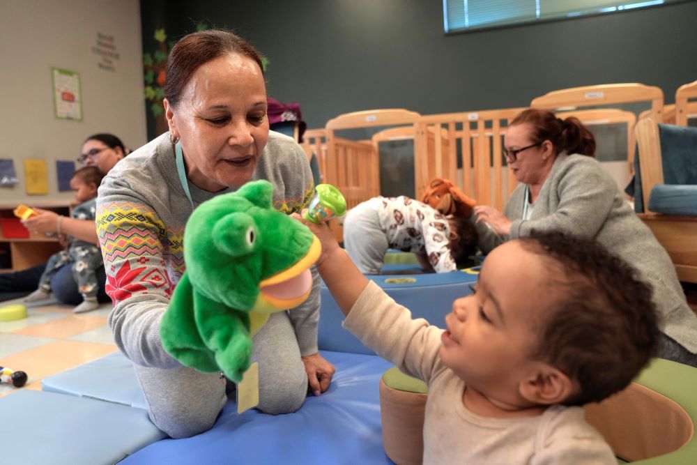 Volunteer Ydalina Luna Sosa uses a frog puppet for entertainment while supervising 10-month-old Leo Morgenweck. 