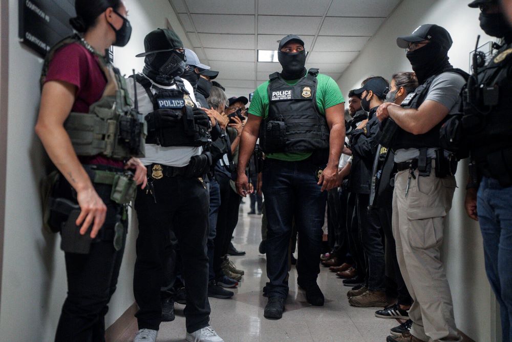 Masked federal agents wait outside an immigration courtroom on July 8 in New York. Masked federal agents wait outside an immigration courtroom on July 8 in New York.