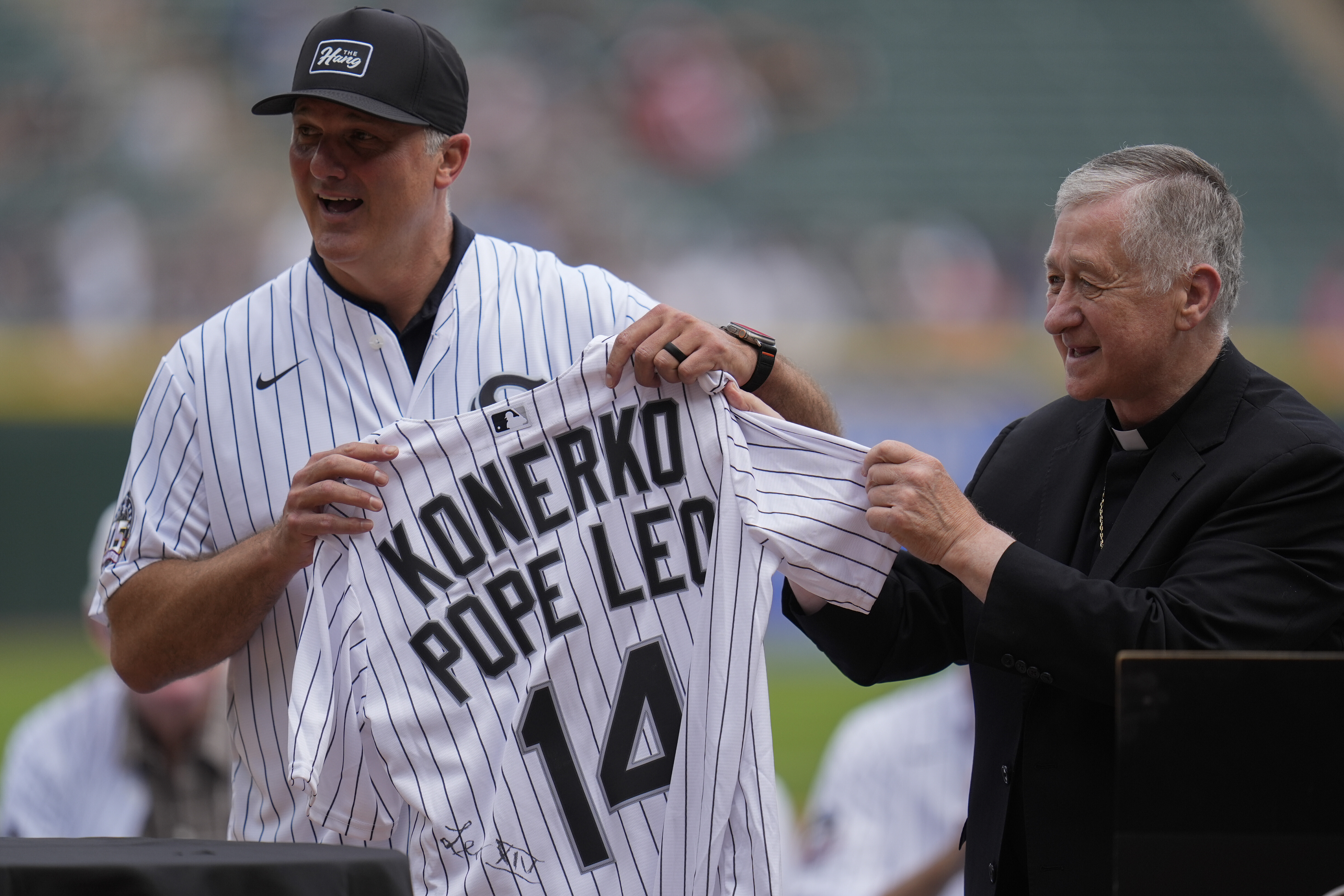 Cardinal Blase Cupich, right, presents former White Sox player Paul Konerko with a jersey signed by Pope Leo XIV during a ceremony honoring the 2005 World Series Champions before a baseball game between the Cleveland Guardians and Chicago White Sox, Saturday, July 12, 2025, in Chicago. (AP Photo/Erin Hooley)