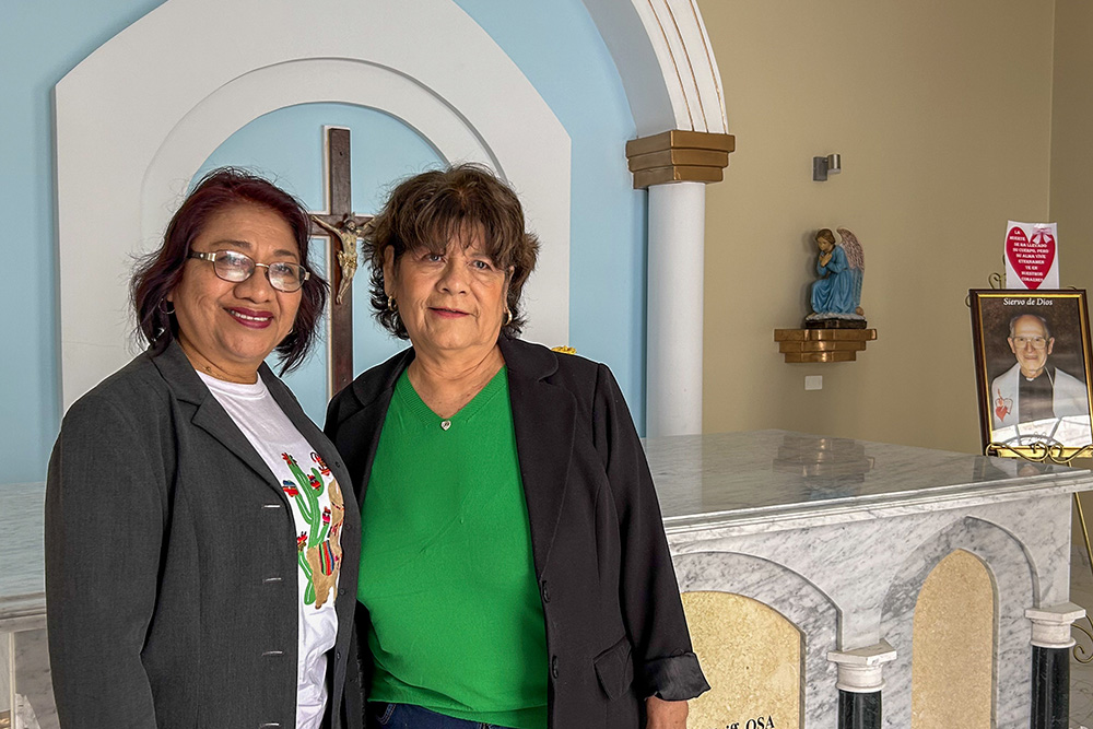 Lola Chávez, a sinistra, ed Elena Lozada Seminario stanno per una foto davanti alla tomba del vescovo agostiniano John McKniff di Chulucanas, Perù, a St. Joseph the Worker Parish. (Foto NCR/Justin McLellan)