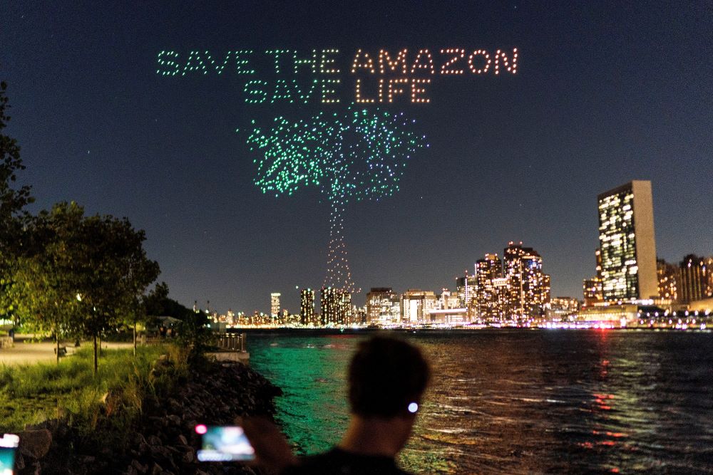 People watch drones creating a 3-D display outside the United Nations Headquarters in 2023.