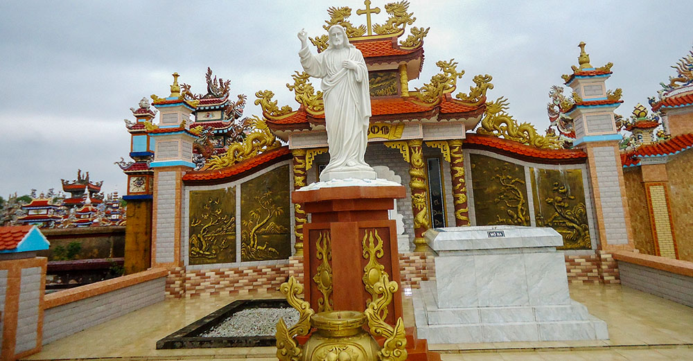 Una statua di Gesù si trova tra le tombe dei genitori di Paul Van Cong Phuc. Suo padre riposa a destra, mentre sua madre, ancora viva, visita regolarmente il sito per pregare. (Joachim Pham)