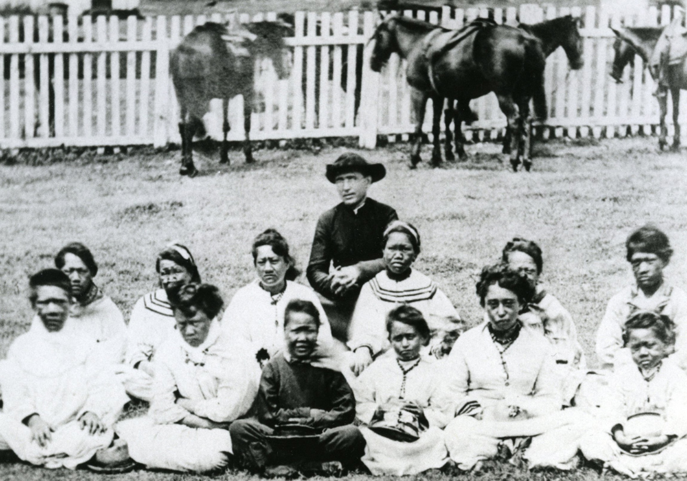 St. Damien de Veuster is pictured with young people at the settlement for those with Hansen's disease, or leprosy, on the Hawaiian island of Molokai. (CNS) St. Damien de Veuster is pictured with young people at the settlement for those with Hansen's disease, or leprosy, on the Hawaiian island of Molokai. (CNS)