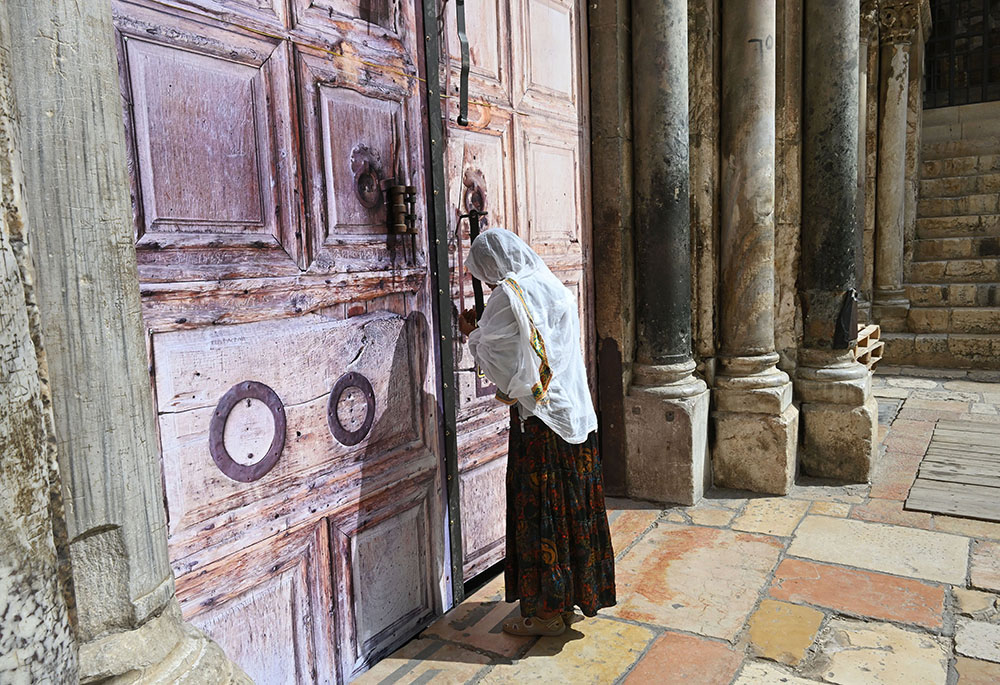 An Ethiopian Christian woman prays at the locked doors of the Church of the Holy Sepulcher in the Old City of Jerusalem March 4, 2026, on day five of the U.S.-Israel war with Iran. The church and other religious sites as well as stores were locked shut by order of the Israeli government as Iranian ballistic missiles were fired at Israel. (OSV News/Debbie Hill)