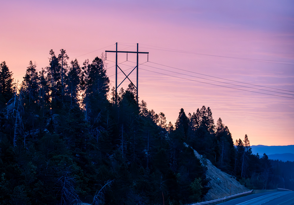Power lines and a pylon are seen at dawn in the mountains of Montana. (Dreamstime/Brian Grimmer)