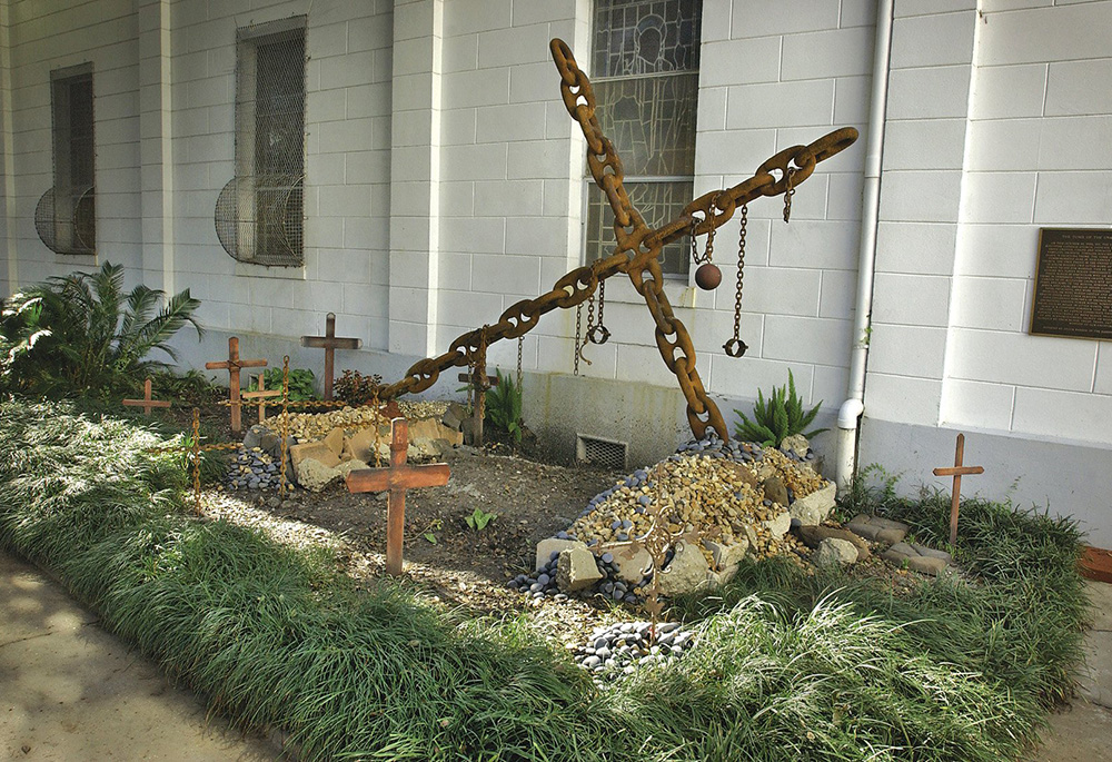 The "Tomb of the Unknown Slave" is seen in a courtyard adjacent to St. Augustine Catholic Church in New Orleans. The memorial shows symbols of slavery such as a massive chain constructed in the shape of a cross and metal neckbands, shackles and unmarked crosses. (CNS/Clarion Herald/Frank J. Methe)