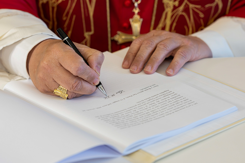 Pope Leo XIV signs Magnifica Humanitas at the Vatican's Synod Hall May 15, 2026. (OSV News/Vatican Media/Simone Risoluti)