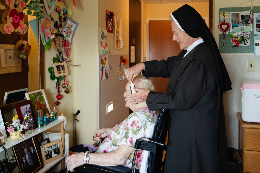 An undated photo shows a Carmelite sister combing a resident's hair at Ozanam Hall in Bayside, the New York borough of Queens. On July 30, 2026, a judge temporarily shielded four orders of women religious and Catholic healthcare ministries from enforcement of a New York state law allowing physicians to aid terminally ill adults in dying by suicide. (OSV News/Courtesy Becket)