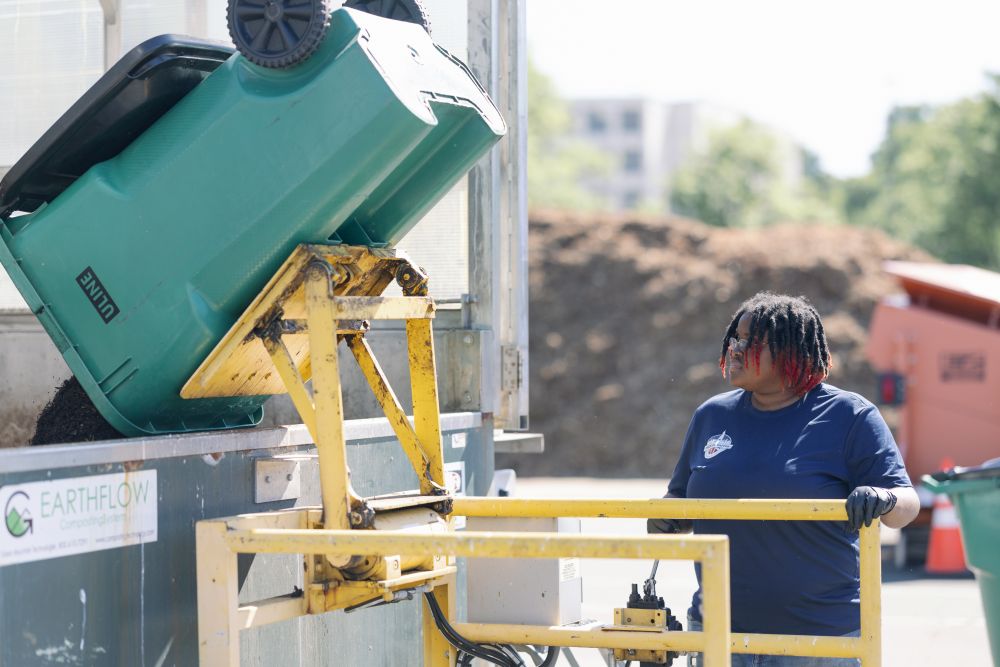 A University of Dayton student empties a bin of food waste into the campus' in-vessel composter. During the academic year, Dayton composts a ton of food waste each day. (Courtesy of University of Dayton)