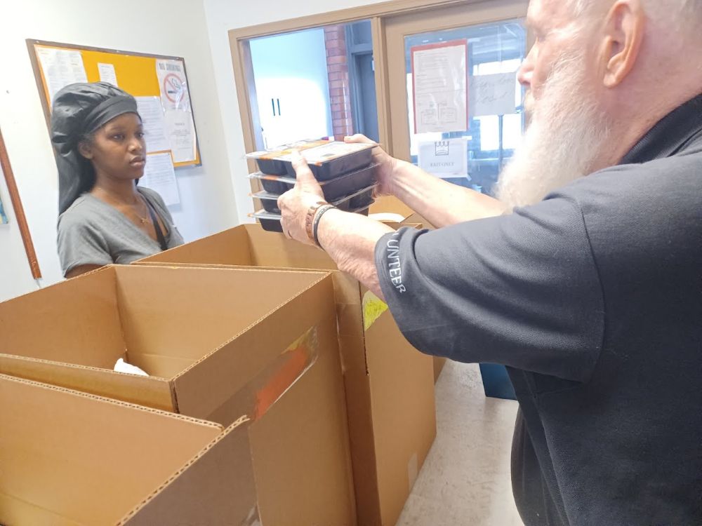 A volunteer at the St. Mary's Parish food kitchen in Dayton, Ohio, hands out meals prepared by Miami Valley Meals. Produce used in the meals is grown at the University of Dayton's Flyer Farm. (Sabrina Furlow)