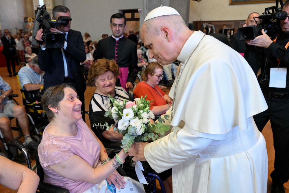 Pope Leo XIV receives a bouquet of flowers from a woman during a meeting with people experiencing illness or disabilities and those receiving support from Caritas in the city's cathedral in Rimini, Italy, Aug. 22, 2026. (CNS/Vatican Media)