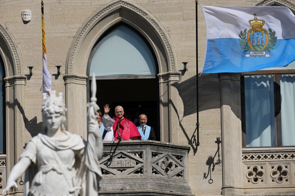 Pope Leo XIV, flanked by Captains Regent Alice Mina, left, and Vladimiro Selva, waves to faithful from the balcony of Palazzo Pubblico (City Hall) during his visit to San Marino Aug. 22, 2026. (AP/Andrew Medichini)