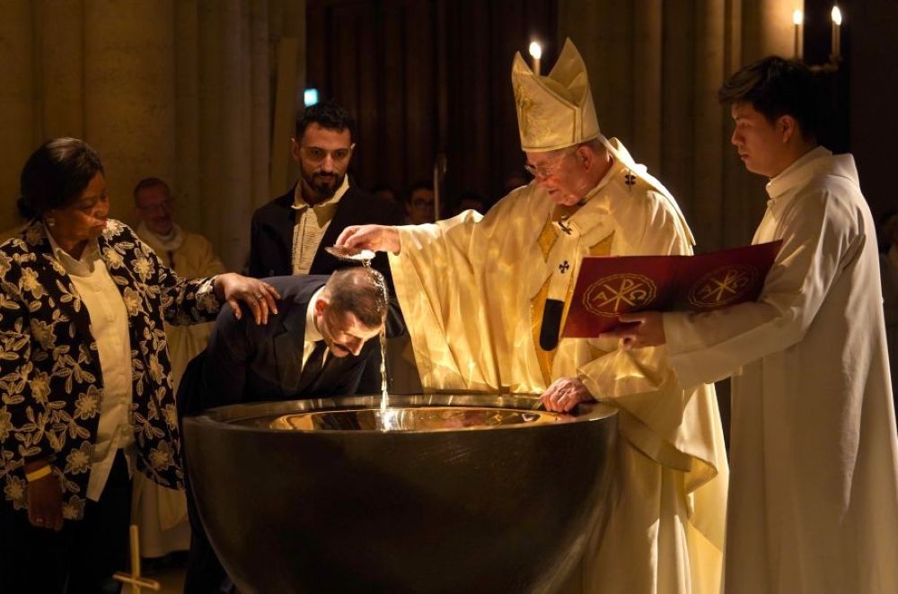 Paris Archbishop Laurent Ulrich baptizes an adult man in the baptismal font of Notre Dame Cathedral in Paris during Easter Vigil April 4, 2026. (OSV News/Courtesy Archdiocese of Paris/Liam Hoarau)