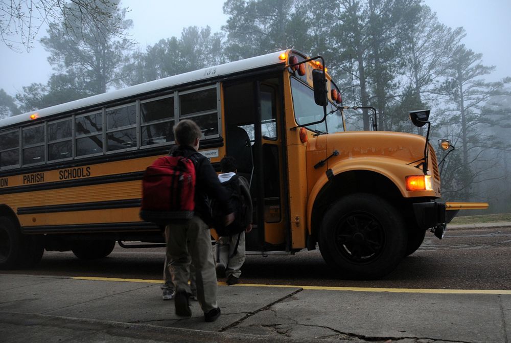Children wait to board school bus. 