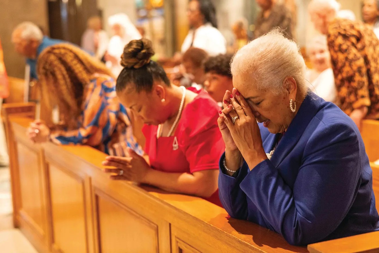 Black Catholic women in prayer at Mass