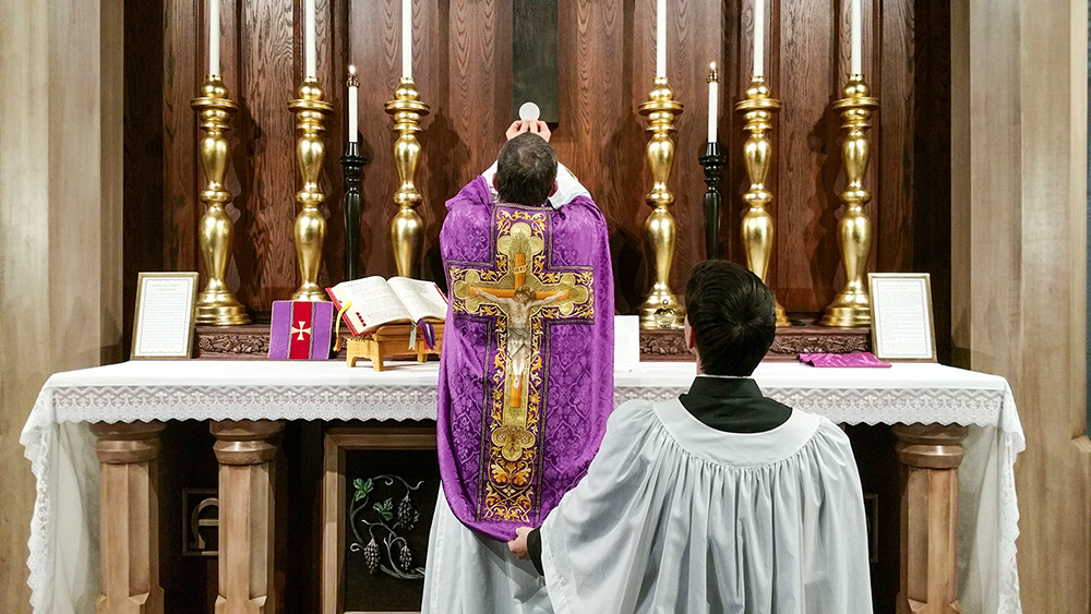 A priest elevates the Eucharist during a Latin Mass. (RNS/Andrew Gardner/Creative Commons)